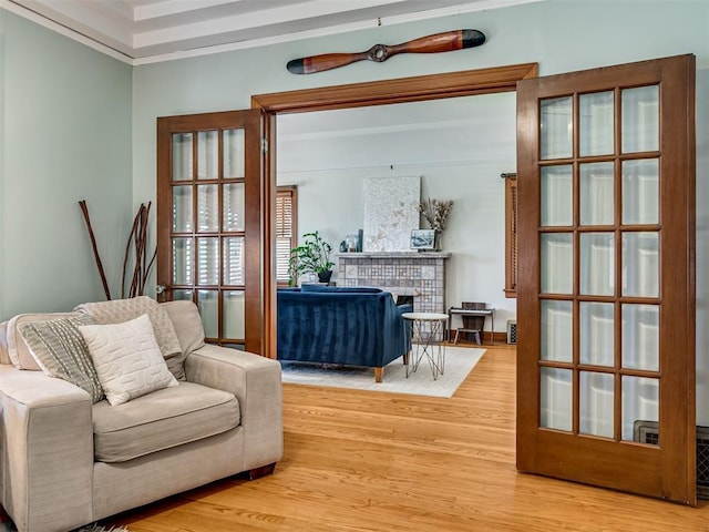 sitting room with light wood-style floors, crown molding, and a brick fireplace