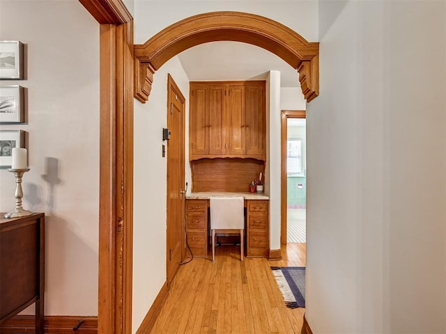hall featuring arched walkways and light wood-style flooring