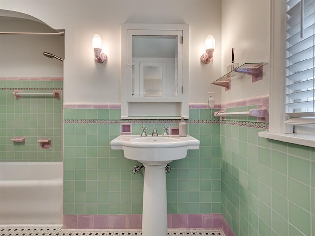 bathroom featuring washtub / shower combination, tile walls, and wainscoting