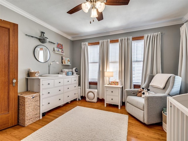 living area featuring crown molding, a ceiling fan, a wealth of natural light, and light wood-style flooring