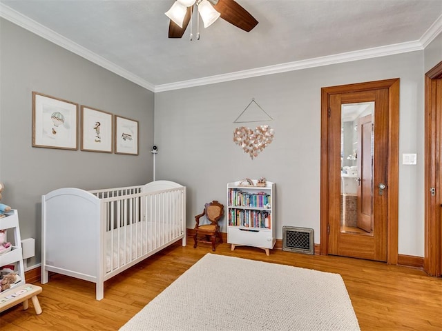 bedroom featuring visible vents, ornamental molding, baseboards, and wood finished floors