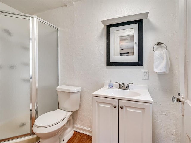 full bathroom featuring wood finished floors, a stall shower, toilet, and vanity