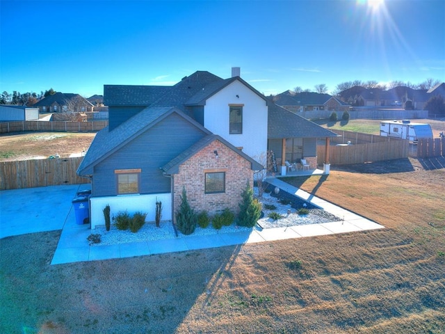 bungalow-style house with a residential view, brick siding, a fenced backyard, a front lawn, and a shingled roof