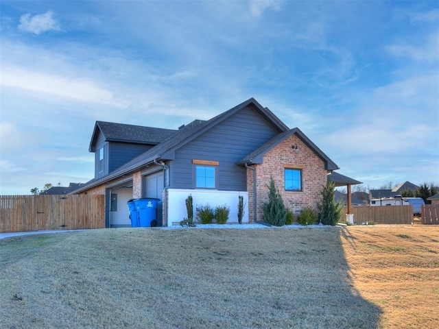view of front of property with brick siding, a garage, fence, and a front yard