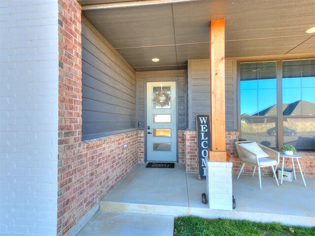 view of exterior entry with covered porch and brick siding