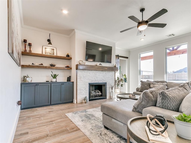 living room with ceiling fan, visible vents, baseboards, ornamental molding, and light wood-style flooring