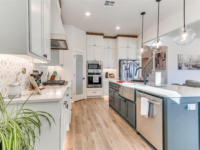 kitchen with visible vents, a sink, premium range hood, white cabinets, and stainless steel appliances