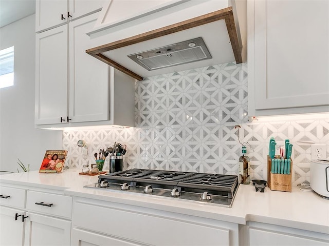 kitchen featuring stainless steel gas cooktop, light countertops, extractor fan, white cabinetry, and tasteful backsplash
