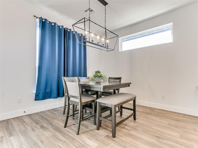 dining area with baseboards, a notable chandelier, light wood-style flooring, and visible vents