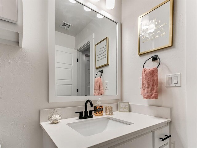 bathroom featuring vanity, a textured wall, and visible vents
