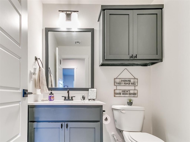 half bath with visible vents, toilet, and vanity
