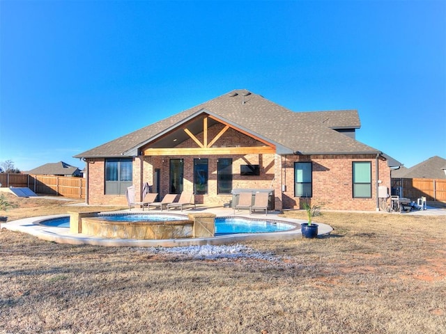 rear view of property featuring fence, a patio, a shingled roof, and brick siding