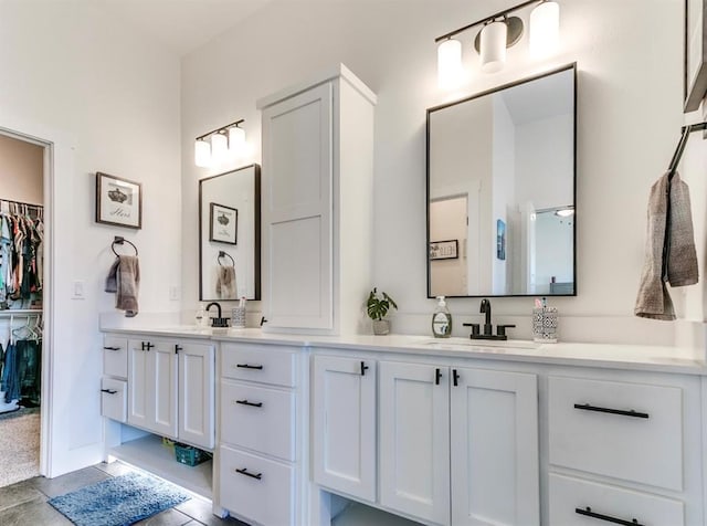 full bathroom with double vanity, a spacious closet, and a sink