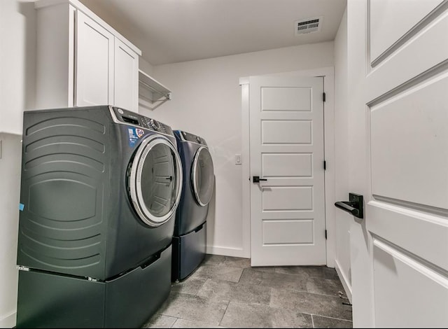 laundry room featuring washer and dryer, cabinet space, baseboards, stone finish flooring, and visible vents