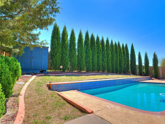 outdoor pool with fence, a storage unit, and an outdoor structure