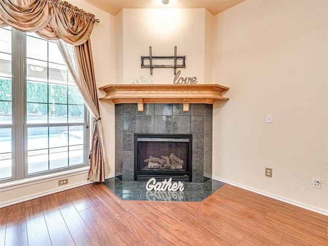 room details with baseboards, wood finished floors, and a tiled fireplace