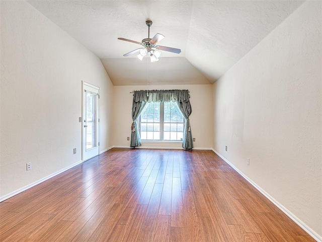 spare room with a textured ceiling, ceiling fan, vaulted ceiling, and wood finished floors
