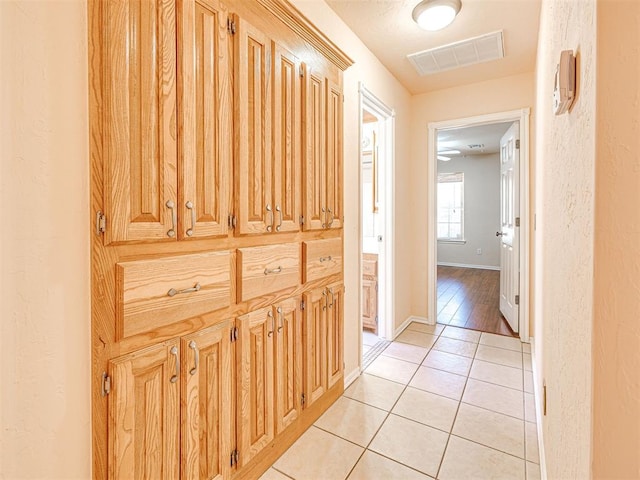 hallway featuring visible vents, baseboards, and light tile patterned floors