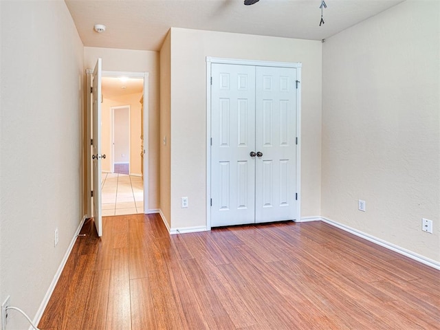 unfurnished bedroom featuring baseboards, wood finished floors, and a closet
