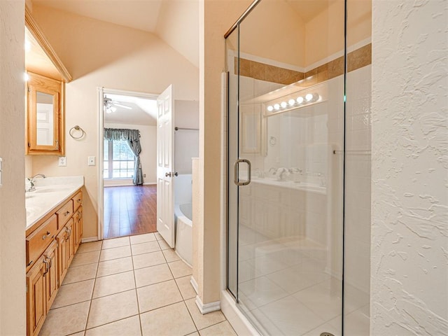 full bath featuring a sink, tile patterned flooring, vaulted ceiling, a garden tub, and a stall shower