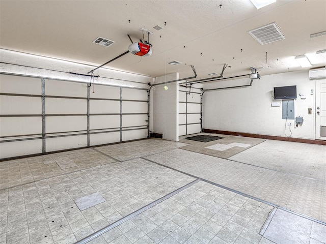 garage featuring baseboards, visible vents, a wall unit AC, and a garage door opener