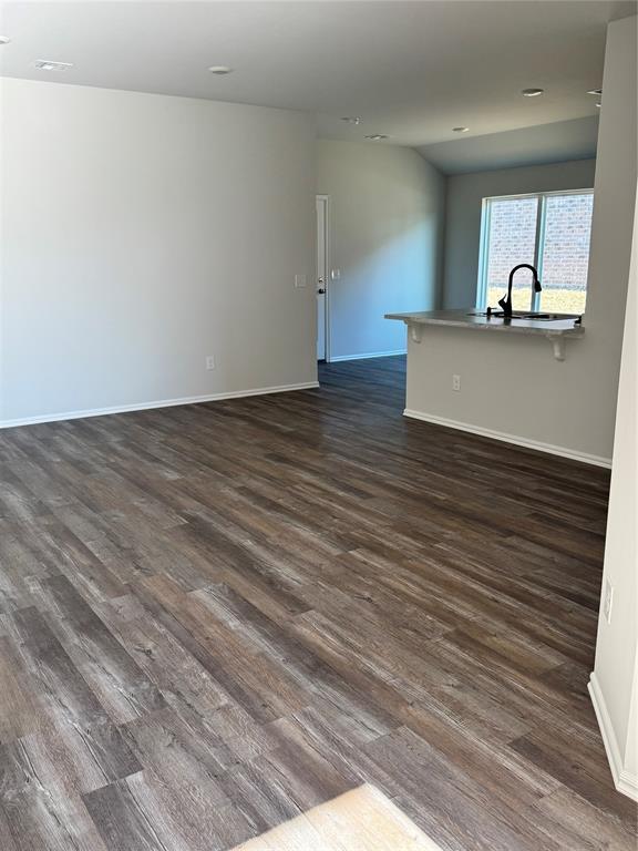 437 Kale Rd, Tuttle, OK 73089 - unfurnished living room with dark wood-style floors, baseboards, and a sink