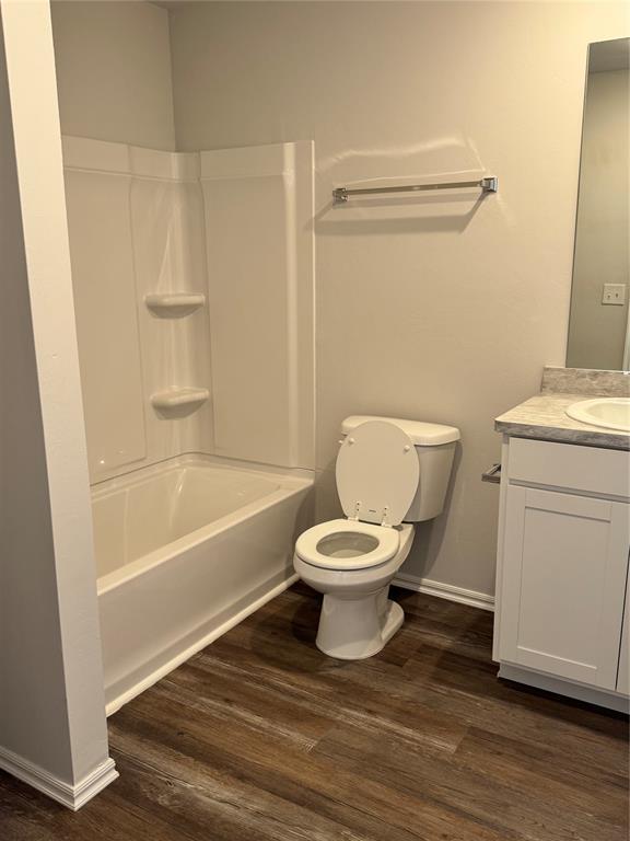 437 Kale Rd, Tuttle, OK 73089 - full bathroom with vanity, toilet, wood finished floors, baseboards, and washtub / shower combination
