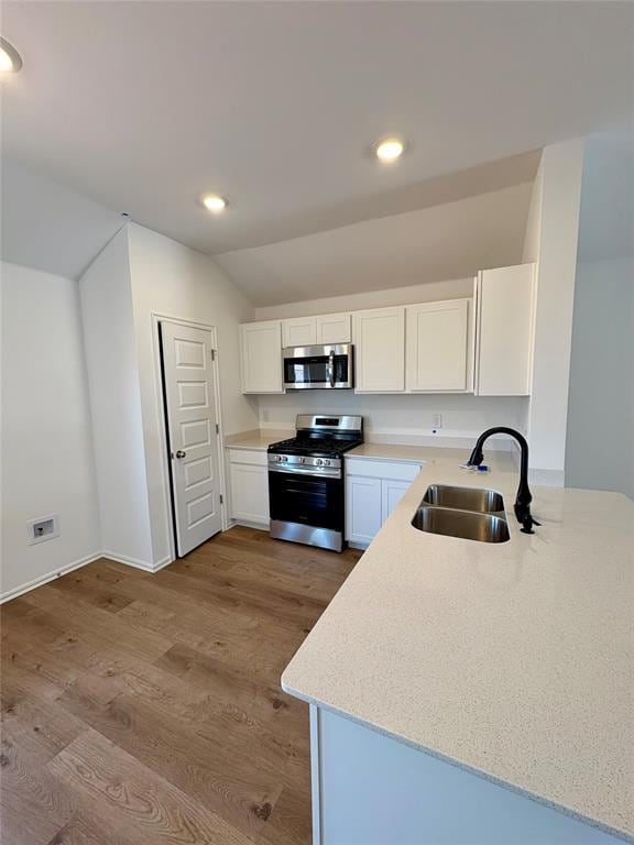 424 Kale Rd, Tuttle, OK 73089 - kitchen featuring appliances with stainless steel finishes, white cabinetry, wood finished floors, recessed lighting, and lofted ceiling