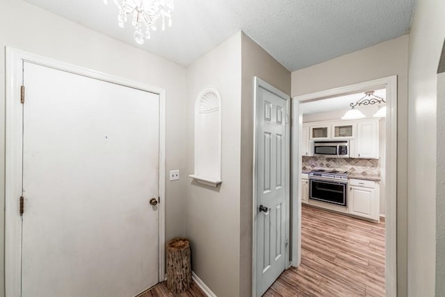 237 E 30th St, Edmond, OK 73013 - hallway featuring light wood-style flooring, a chandelier, and baseboards