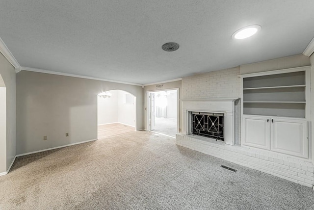 237 E 30th St, Edmond, OK 73013 - unfurnished living room with crown molding, a textured ceiling, carpet flooring, arched walkways, and a brick fireplace
