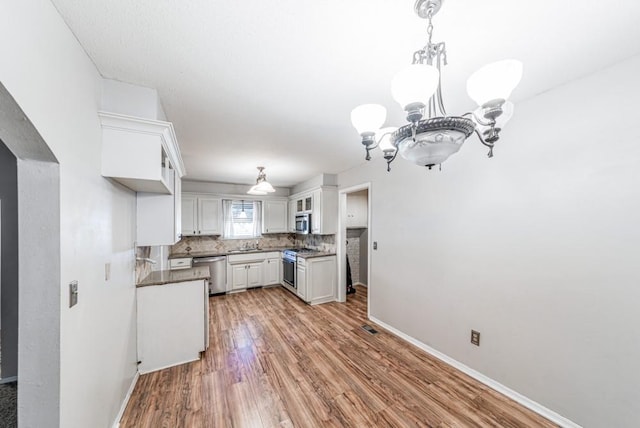 237 E 30th St, Edmond, OK 73013 - kitchen featuring appliances with stainless steel finishes, a chandelier, baseboards, light wood-style floors, and a sink