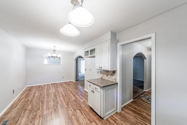 237 E 30th St, Edmond, OK 73013 - kitchen with arched walkways, white cabinetry, a chandelier, and light wood finished floors