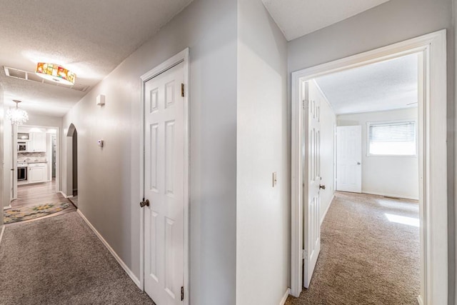 237 E 30th St, Edmond, OK 73013 - hallway with carpet floors, a textured ceiling, arched walkways, and baseboards
