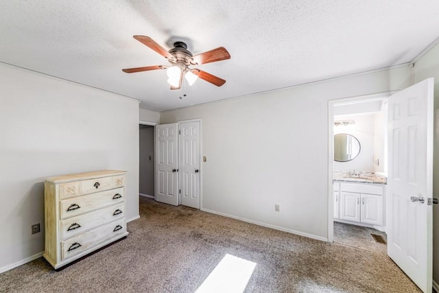 237 E 30th St, Edmond, OK 73013 - unfurnished bedroom with light colored carpet, ensuite bath, a sink, a textured ceiling, and baseboards