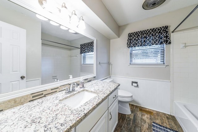 237 E 30th St, Edmond, OK 73013 - bathroom featuring vanity, a wainscoted wall, wood finished floors, toilet, and bathing tub / shower combination