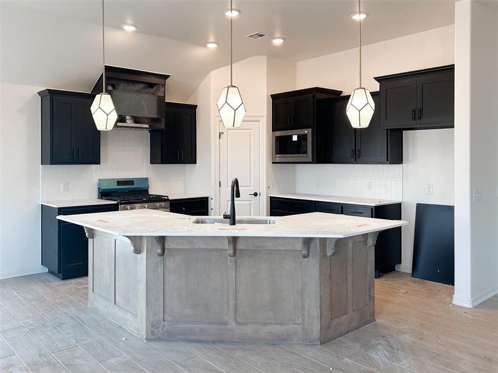 12024 NW 121st Cir, Yukon, OK 73099 - kitchen with appliances with stainless steel finishes, decorative backsplash, a center island with sink, and dark cabinetry
