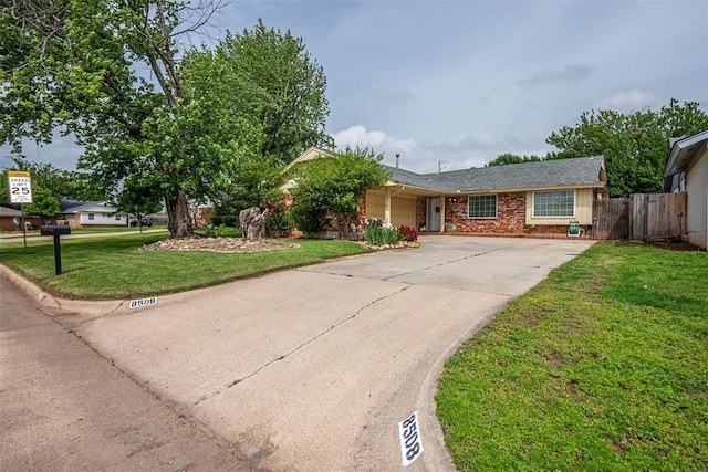 ranch-style house featuring a garage, fence, a front yard, brick siding, and concrete driveway