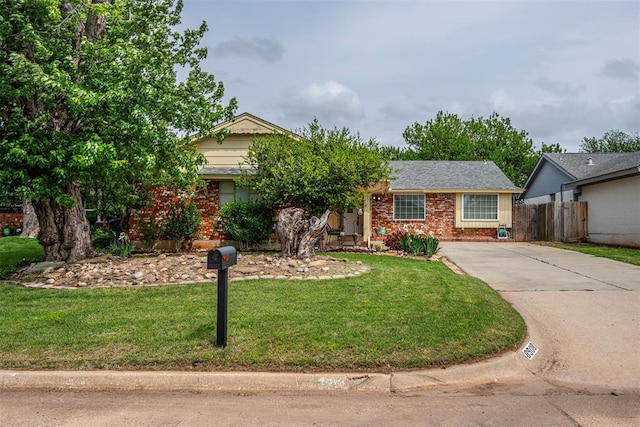 ranch-style house with fence, concrete driveway, a front lawn, and brick siding