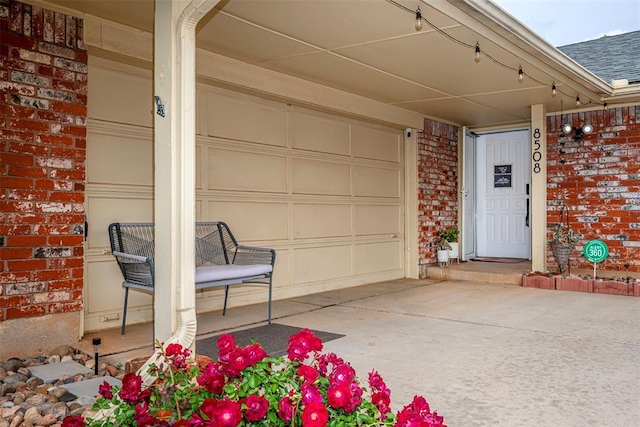 view of exterior entry with brick siding and roof with shingles