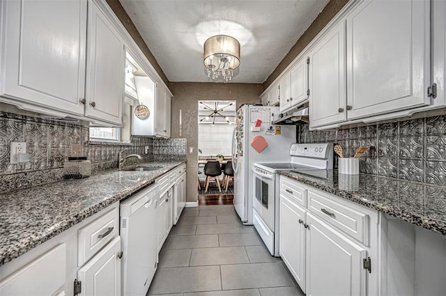 kitchen with white cabinets, a sink, white appliances, decorative backsplash, and under cabinet range hood