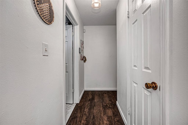 corridor featuring baseboards, a textured ceiling, and wood finished floors