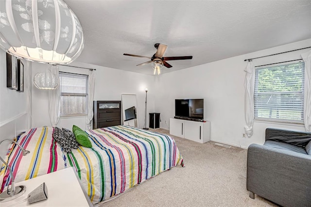 bedroom featuring carpet flooring, a textured ceiling, ceiling fan, and multiple windows
