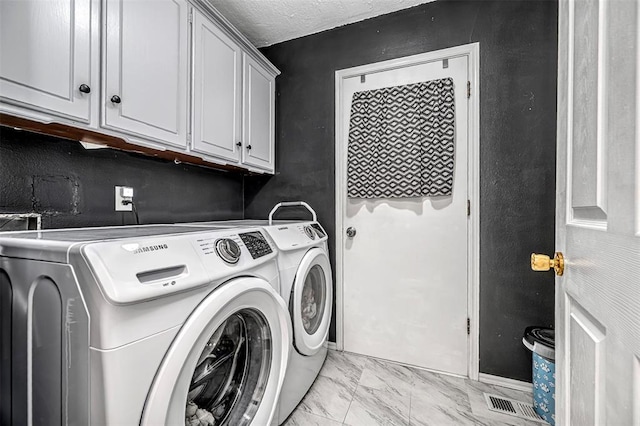 clothes washing area featuring marble finish floor, cabinet space, and washer and dryer