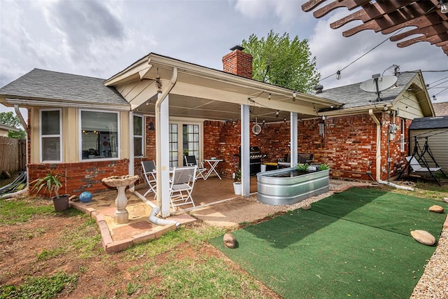 back of house featuring brick siding, fence, a chimney, and a patio area