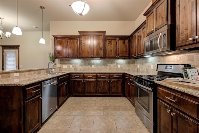 kitchen with a sink, stainless steel appliances, tasteful backsplash, light stone counters, and a peninsula