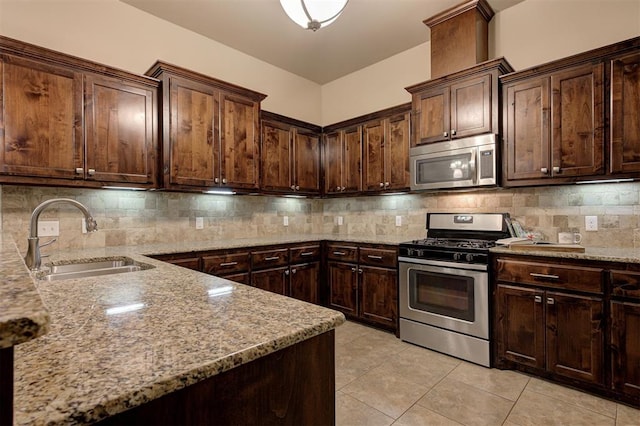 kitchen featuring light tile patterned flooring, stainless steel appliances, light stone countertops, and a sink