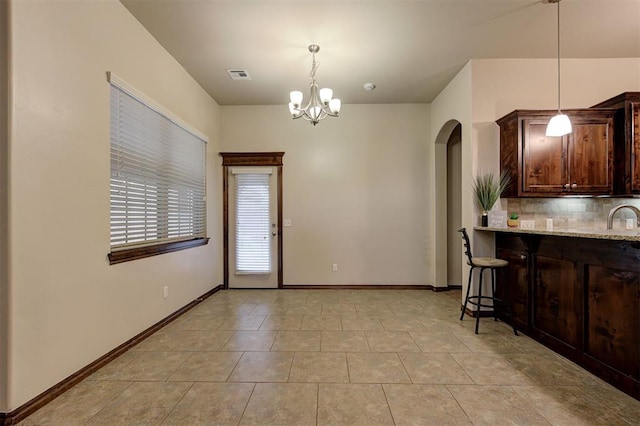 kitchen with a chandelier, visible vents, backsplash, arched walkways, and hanging light fixtures