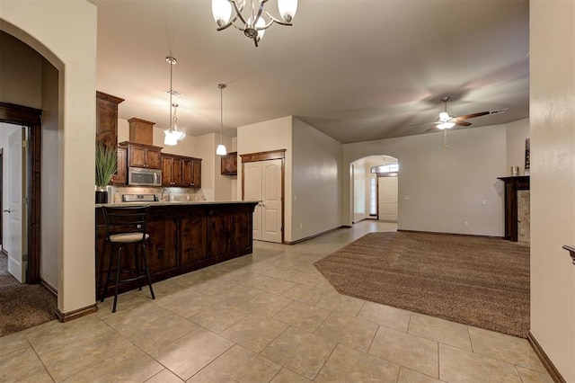 kitchen featuring arched walkways, stainless steel microwave, ceiling fan, baseboards, and a peninsula