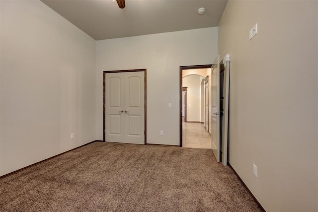 unfurnished bedroom with ceiling fan, light carpet, and baseboards