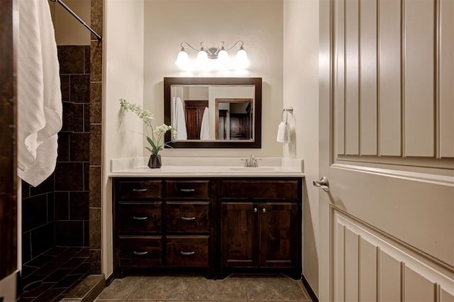 bathroom featuring tiled shower and vanity
